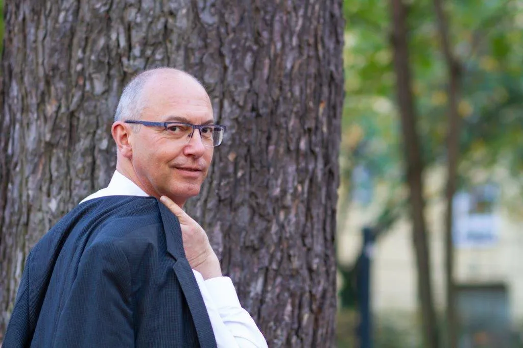 Reinhard Giese lehnt entspannt an einem Baum im Freien